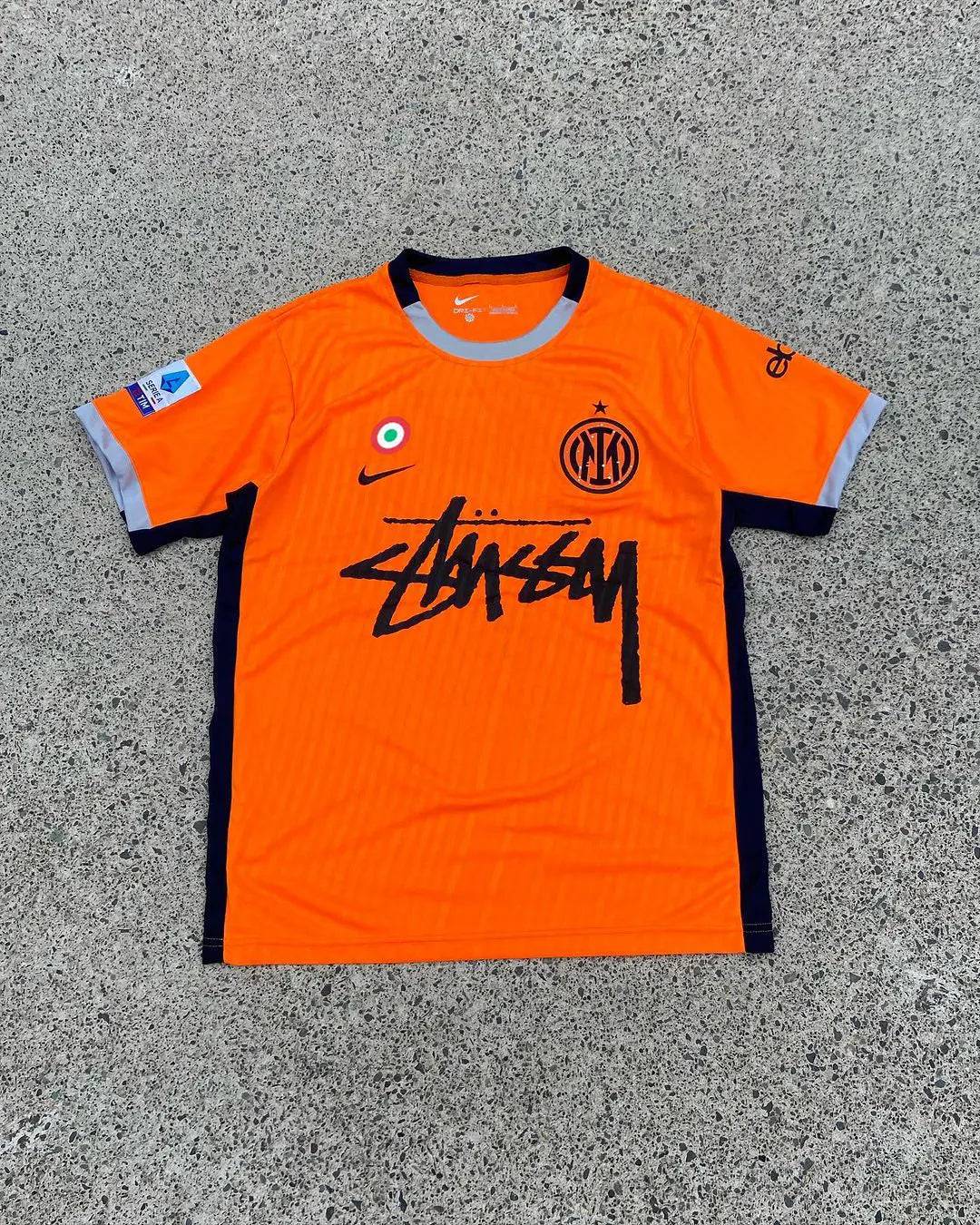 Inter Milan x Stussy Limited Edition Jersey in vibrant orange, featuring the Inter Milan crest and Stussy logo, blending football heritage with streetwear style.