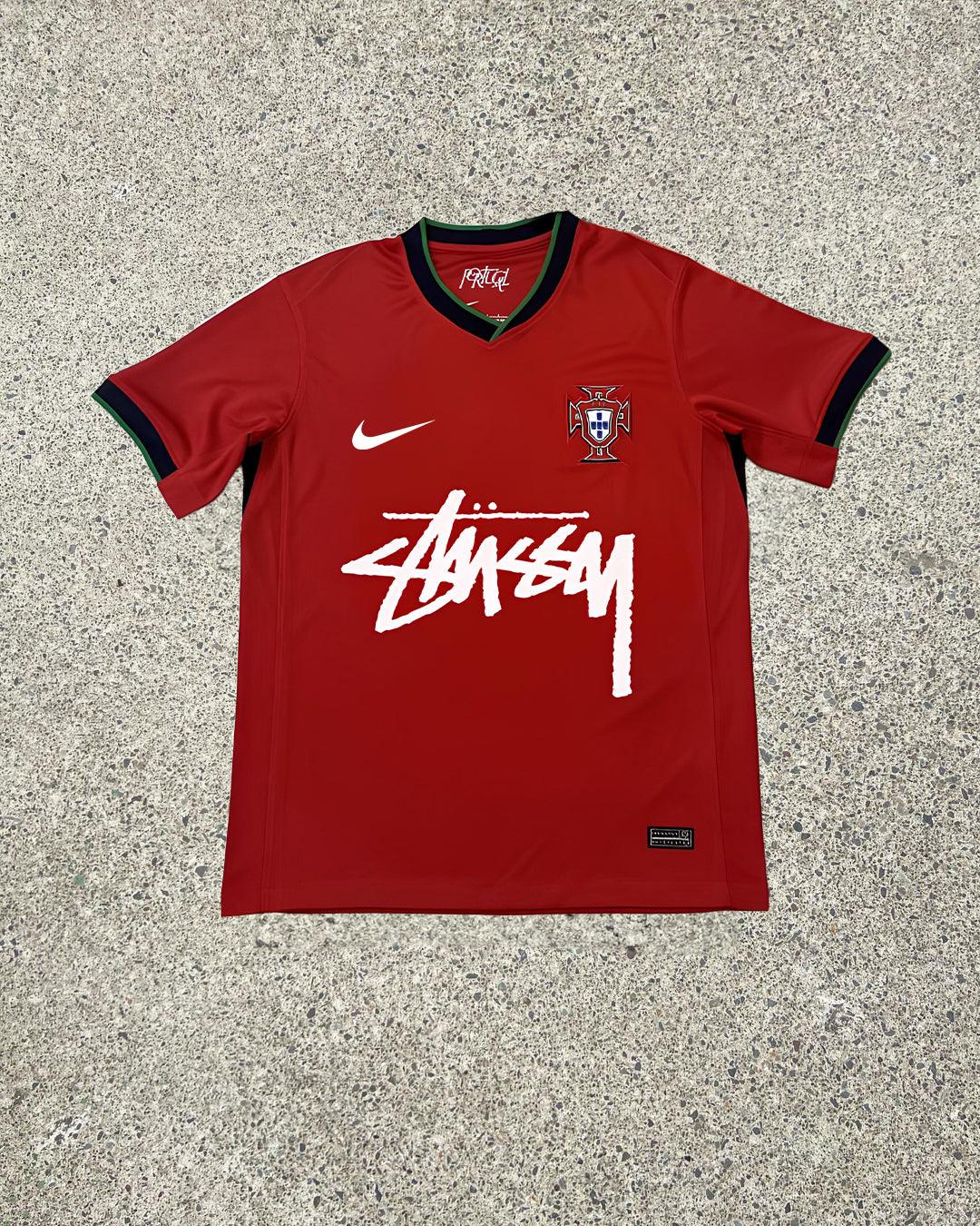 Stussy Portugal Edition Jersey featuring vibrant red and green colors, Stussy branding, and the Portugal national crest, celebrating the fusion of streetwear and football.